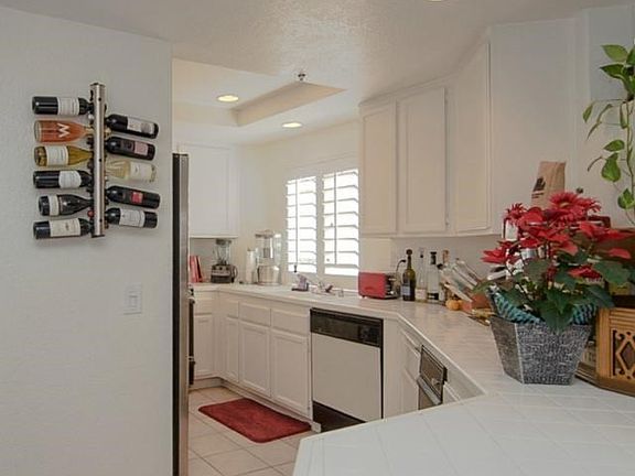 Long tile counters, bright white cabinetry, and recessed lighting make this kitchen a focal point in the home.
