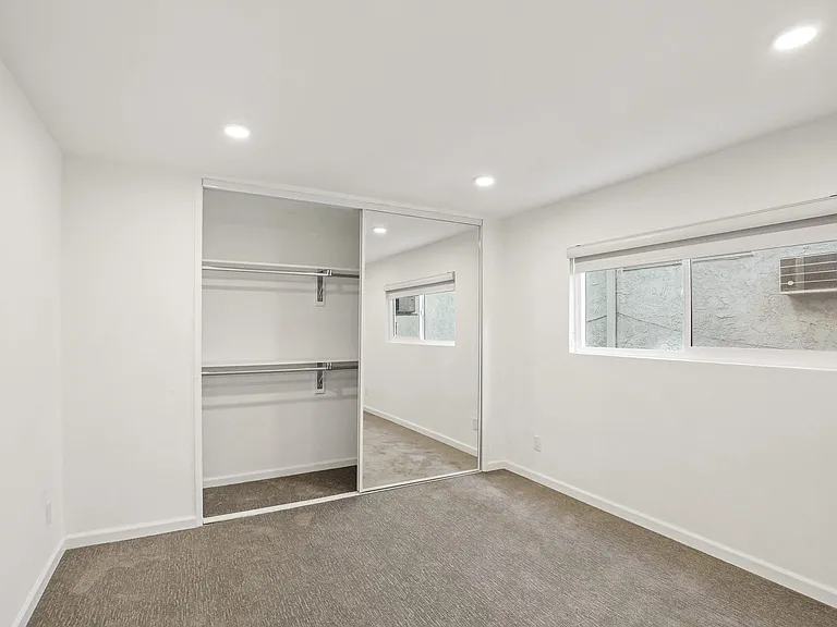 Bedroom with Mirrored Closet, Recessed Lighting, and Large Window
