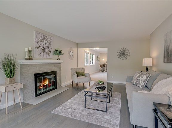Charming living room with wall of windows, wood burning fireplace, refinished hardwood floors with a touch of gray, new trim and new paint.