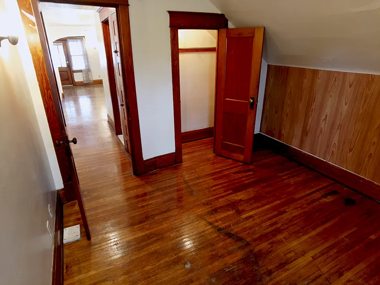 Bedroom looking into the hallway. The original hardwood floor extends into the spacious closet, which provides plenty of storage.