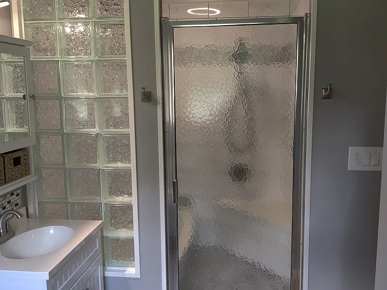 Glass block wall and wet room with tub, shower and marble corner seat. Tile walls, custom cieling with LED light, night light and blue tooth speaker built in. backsplash tile trim and custom shower floor.