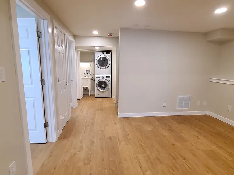 Bedrooms and hall closet on the left, living room on the right, hallway past stairs and toward laundry area