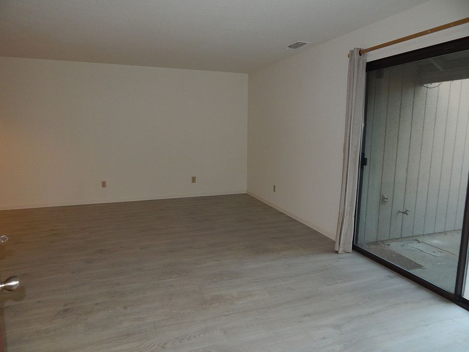 As you step inside, you're greeted by a spacious open-concept living area with modern flooring and neutral paint, perfect for any decor style. The large sliding glass door brings in natural light and leads to a private patio space.