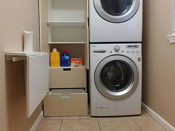 Laundry room with 5 year old stacked LG front load washer and dryer, Ikea storage unit with soft close doors, and folding table that collapses to save space. There is also a small pet door to this room making it a good place for a litter box.