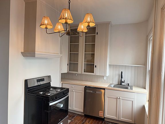 Light-filled kitchen with butcher block countertops, stainless steel appliances, and gas stove with custom range hood