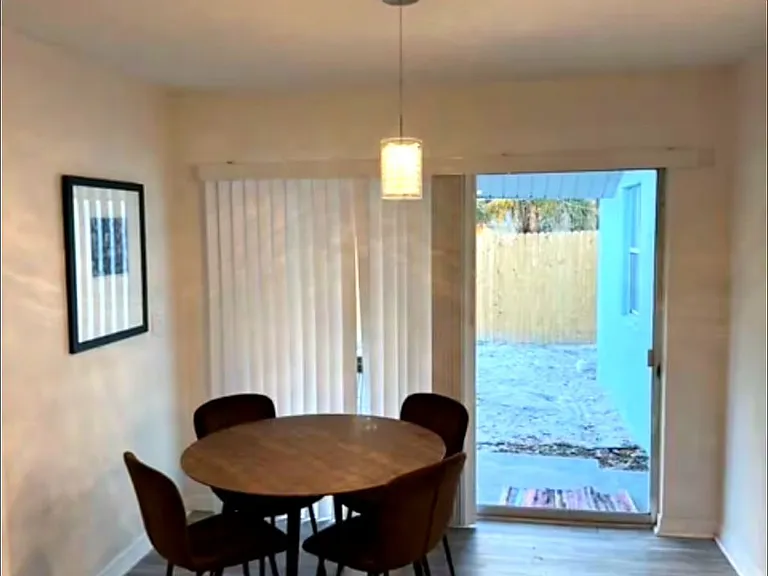 Dining area with round wood table, modern chairs, pendant lighting, and sliding door to the backyard