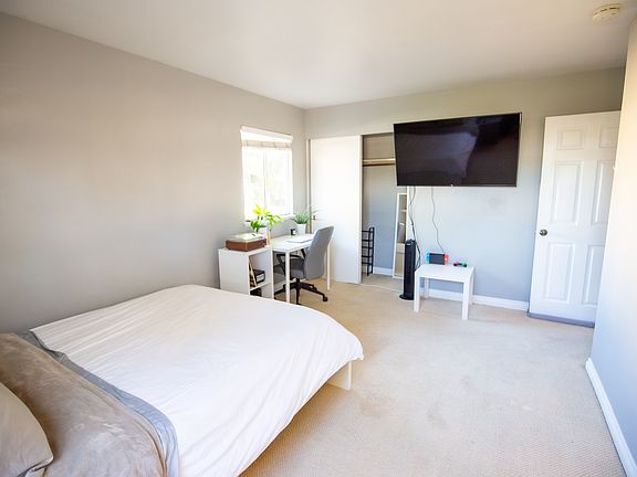 Fully furnished room with queen bed, mattress, desk, chair, tower fan, shelving for organization, 50 inch smart TV, etc