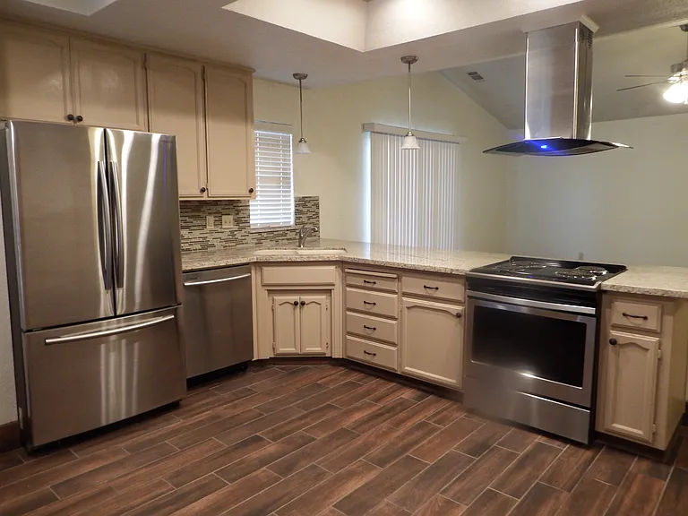All electric kitchen with stainless steel appliances (refrigerator, dishwasher and stove), granite counter top and modern range hood.