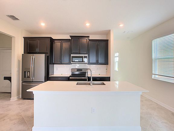 Open kitchen with slate color stainless steel appliances and quartz countertops. Large island for family and friends