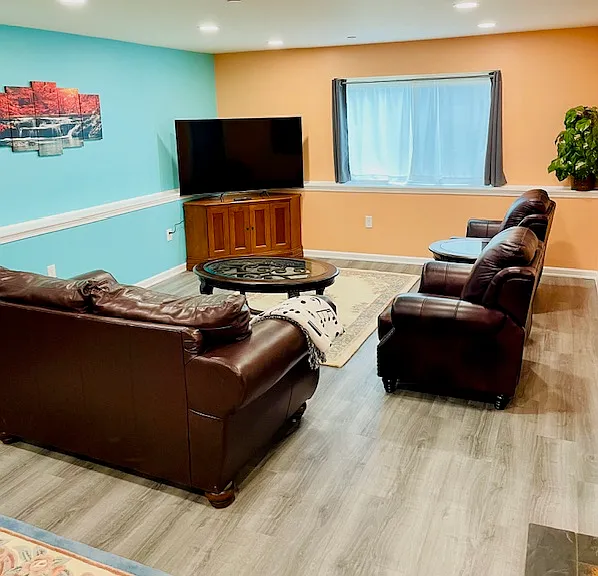 Living room with large TV, entertainment center, loveseat, two recliners, and two coffee tables.