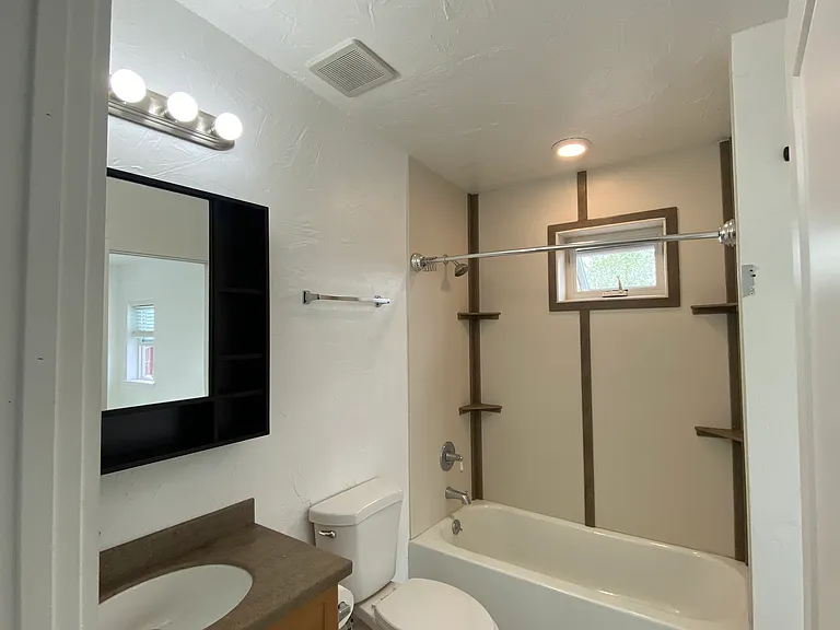 Thoughtfully designed full bathroom offering a classic tub/shower combination, elegant vanity sink, and abundant built-in storage, with a dual entry: a discreet pocket door from the master bedroom and a hallway door.
