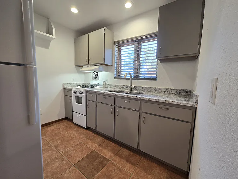 Kitchen area with gas stove, cabinets and new granite tops with stainless steel sink