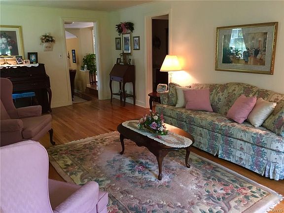 Large formal living room with hardwood floors and crown molding leads to foyer and breakfast room.
