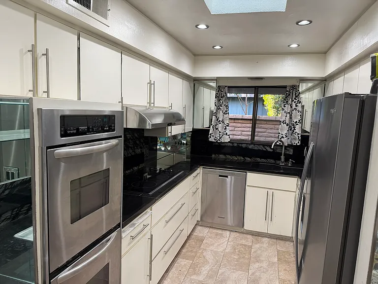 Kitchen with granite countertops, cooktop, double oven, dishwasher, disposal, refrigerator, and wet bar.