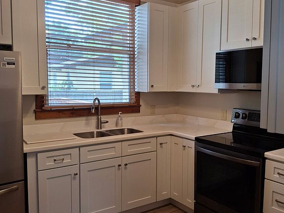 all new kitchen with plank tile floor coastal white shaker cabinets beautiful designer countertop stainess appliances large pantrey coffee bar
