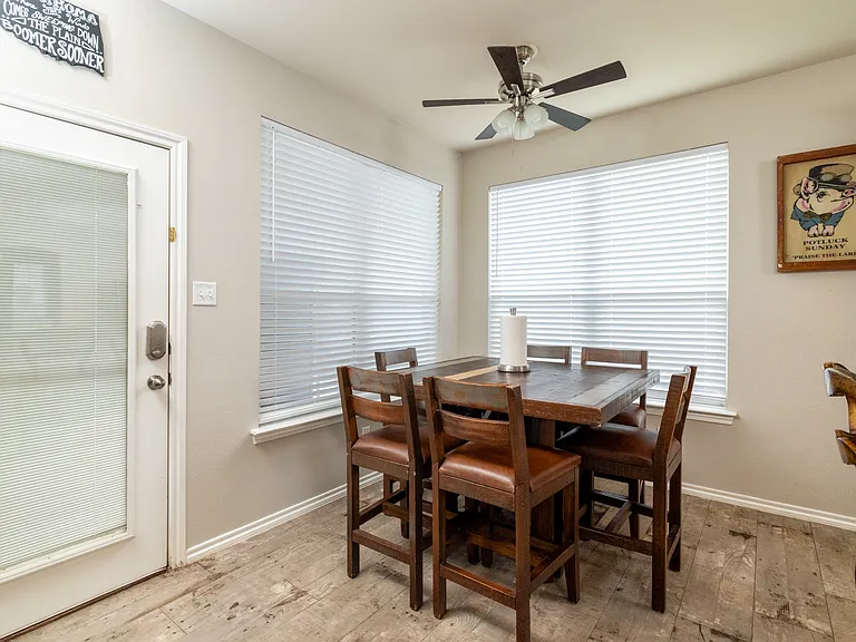 Bright dining area with a wooden table for six, large windows for natural light, and easy access to the backyard_perfect for family meals or entertaining guests in style.