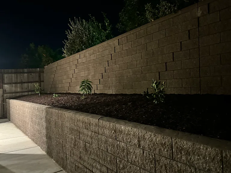 Backyard with retaining wall and plants and weed protection with fabric and bark (mulch)