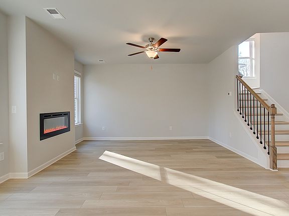 Spacious open Pelham family room with LVP flooring, center electric fireplace, and natural light at