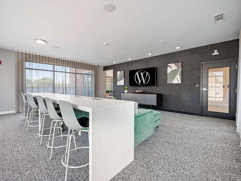 Kick back and relax in the lifestyle amenity center's cozy lounge area with comfortable seating and a TV for entertainment.