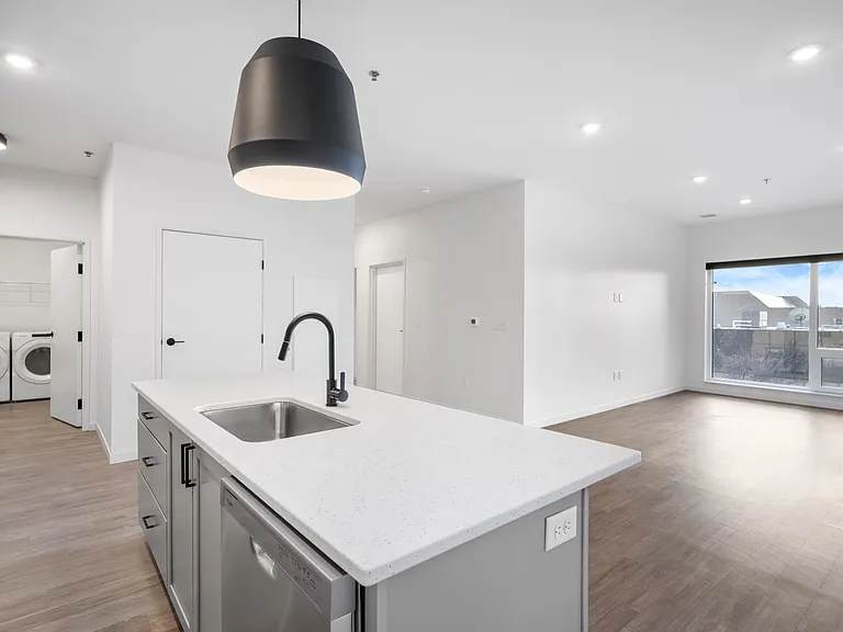 Bright, open-concept apartment with sleek kitchen island, modern pendant light, and in-unit laundry room. Bright, open-concept apartment with sleek kitchen island, modern pendant light, and in-unit laundry room.