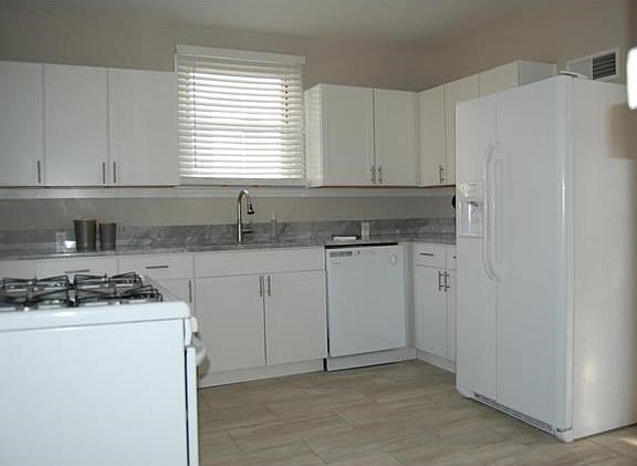 White custom cabinetry with nickel handles, beautiful gray & white granite, new kitchen appliances, new sink & faucet, large pantry and wood like ceramic tile floor complete this fantastic new kitchen.