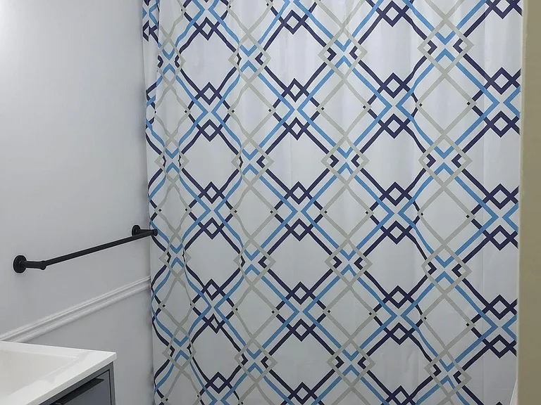Updated bathroom with tiled tub surround, shower curtain, and vanity storage for everyday essentials.