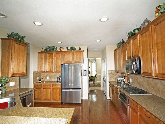 Kitchen with wood floors, stainless GE Profile appliances, gas range & granite