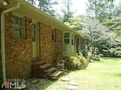 Back exterior of house with back door, windows and beautiful dogwood tree and azaleas at far end of house.