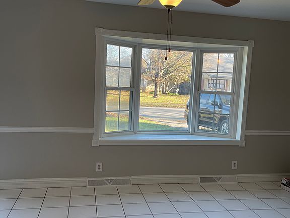 Living room with ceiling fan, tile floors, fireplace, and large bay window. Nice!