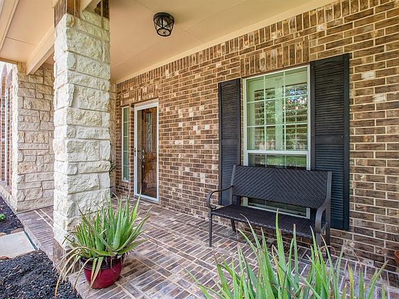 Front porch has brick pavers, stone columns and a storm door.