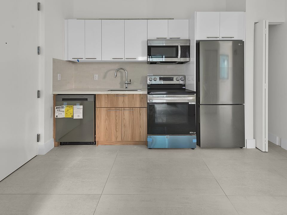 Kitchen with stainless steel appliances and chrome finishes: refrigerator, dishwasher, microwave, and deep sink.