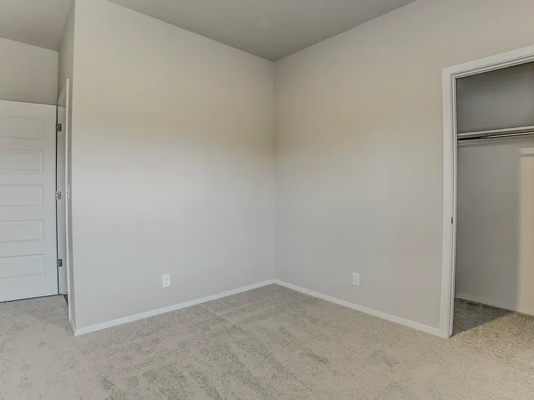 View from inside bedroom. The door on the left leads out to the living room and entrance to the bathroom. Bedroom 2 of 4