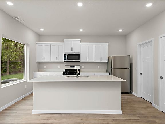 The kitchen has stainless steel appliances and plank flooring.
