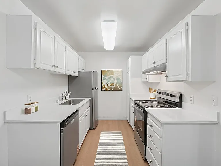 Renovated Package I kitchen with stainless steel appliances, white cabinetry, white quartz countertops, and hard surface flooring