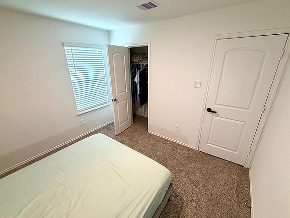 Bedroom with carpet flooring, a window with blinds, and a reach-in closet for convenient everyday storage.
