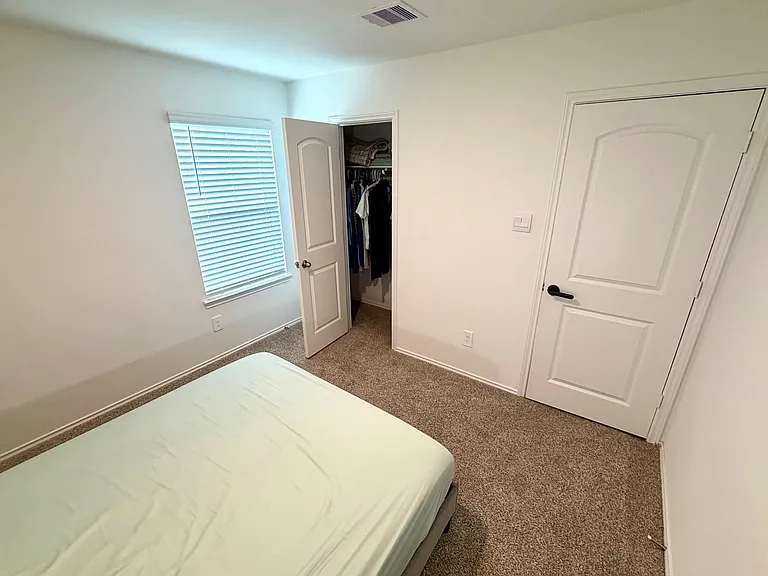 Bedroom with carpet flooring, a window with blinds, and a reach-in closet for convenient everyday storage.
