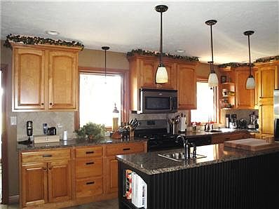 Updated kitchen with maple cabinets, pendant and recessed lighting.
