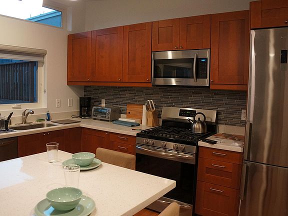 Modern kitchen with quartz countertops, dishwasher, oven, stove, microwave.