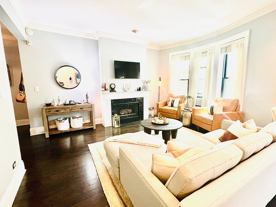 Spacious OPEN and BRIGHT layout living room area with gas fireplace, built in TV mount, new Pella bay windows, and immaculate hardwood flooring