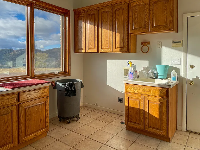 Laundry room featuring utility sink, built in ironing board, and ample storage options and countertop space.