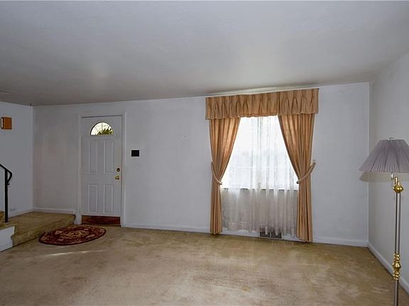 Spacious living room with hardwood flooring beneath the carpeting.