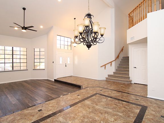 View of front door from dining room with granite inlay floors and sunken living room with hardwood.