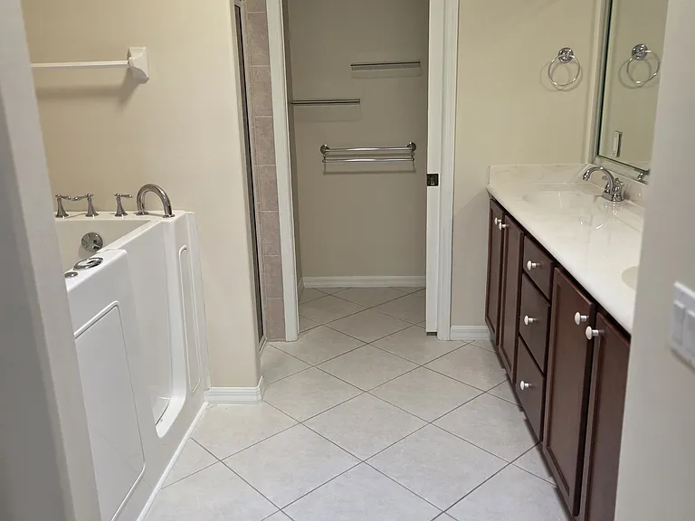Master bathroom with walk-in tub, shower, and dual sink vanities. Toilet in separate room with sliding door.