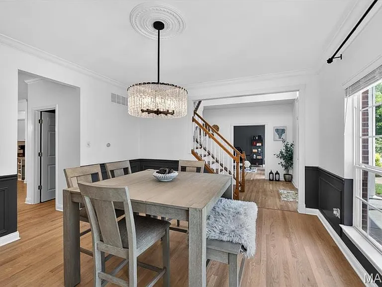 Dining area featuring hardwood flooring, wainscoting, an ornate ceiling medallion, a modern chandelier, and a large window with white trim