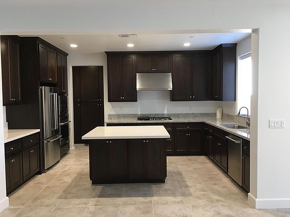 Kitchen with Island for seating. Stainless steel gas stove and exhaust hood. Dishwasher. Pantry storage cabinets at rear of kitchen.
