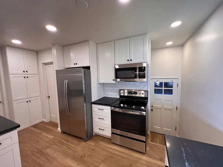 Brand new roomy chef's kitchen with stainless steel appliance and natural stone countertops.