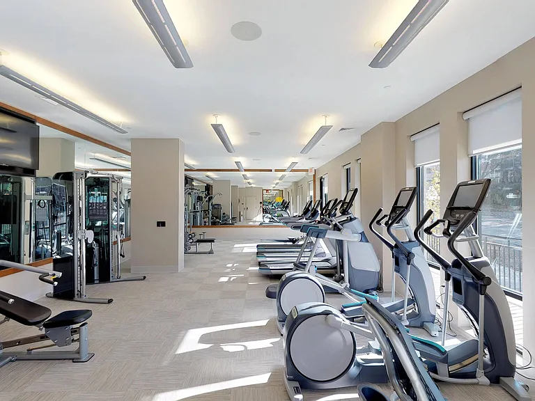 Brightly lit fitness center featuring floor to ceiling windows