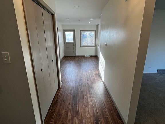 Front entryway. On the left: Large coat closet and stairs up to the 4 bedrooms. To the right: carpeted living room.