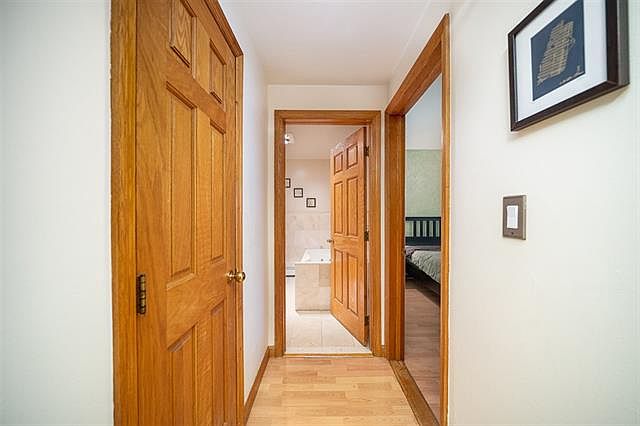 Warm hallway with wood floors and trim, connecting living spaces to bedroom and bath. Cozy, inviting atmosphere.
