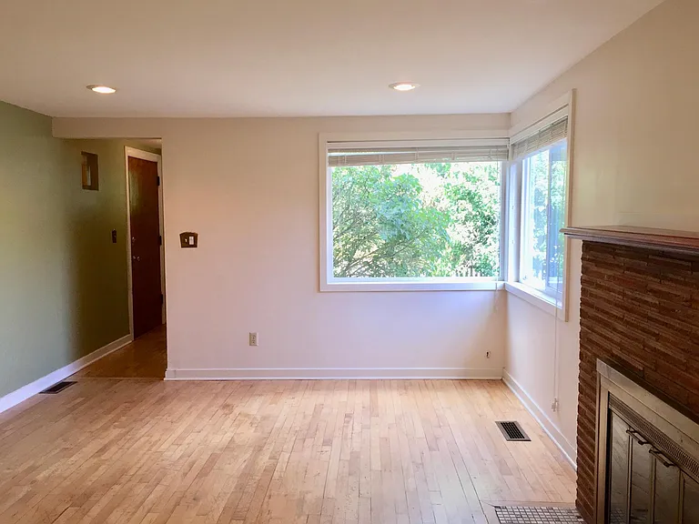 Old photo. Front entry to left of living room. Fresh paint, all white living room,